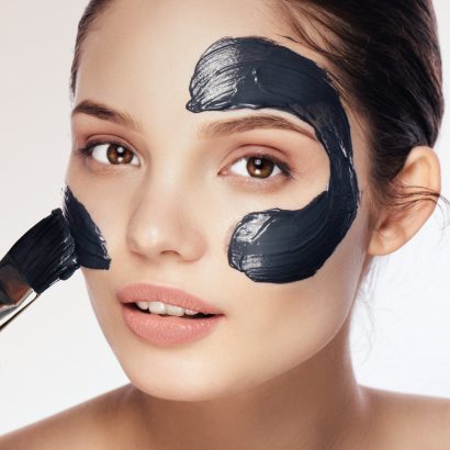 Woman with purifying black mask on her face